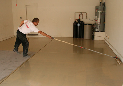 This image shows a man applying epoxy paint on a garage floor.