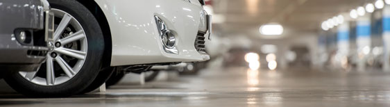 This image shows a white car parked in a parking lot with polished concrete.