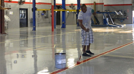 This image shows a man applying epoxy paint on an industrial floor.